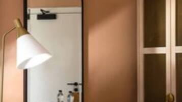 A room with a wooden dresser, a mirror, and a bed with a patterned blanket.