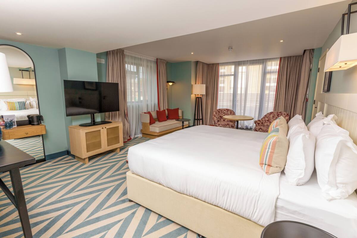 Een hotelkamer met een groot bed, een televisie, een bureau met een lamp en een stoel.