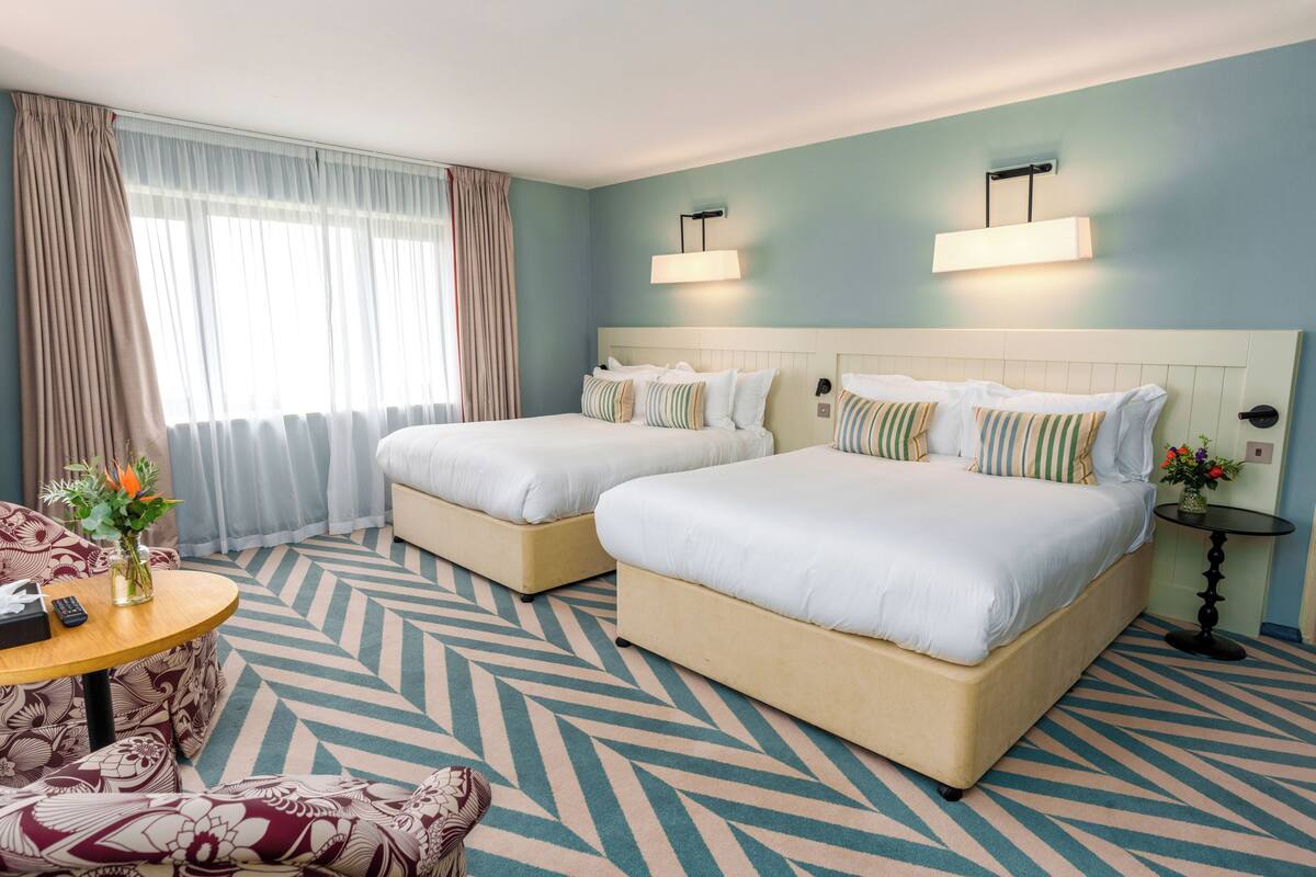 Een hotelkamer met twee bedden, een bank, een tafel en een raam met gordijnen.