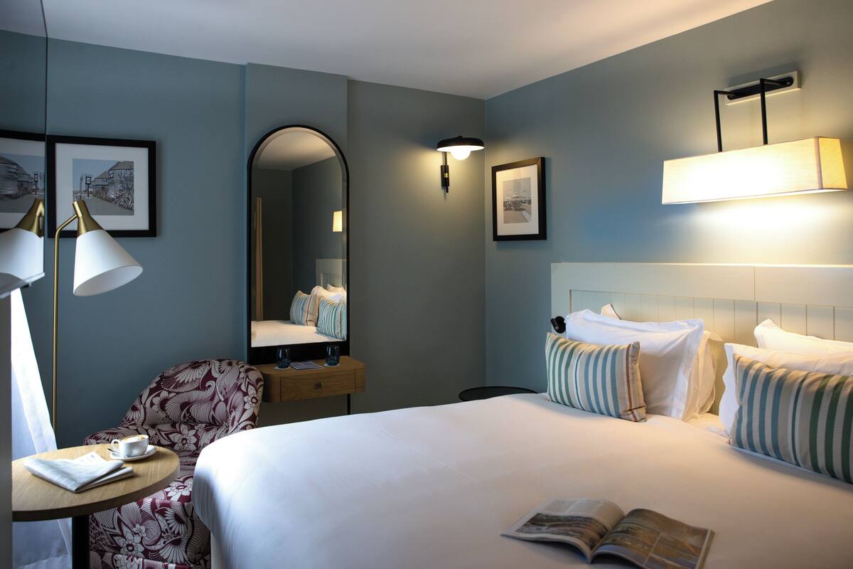 Een hotelkamer met een bed, een bureau met een lamp, een stoel en een spiegel.