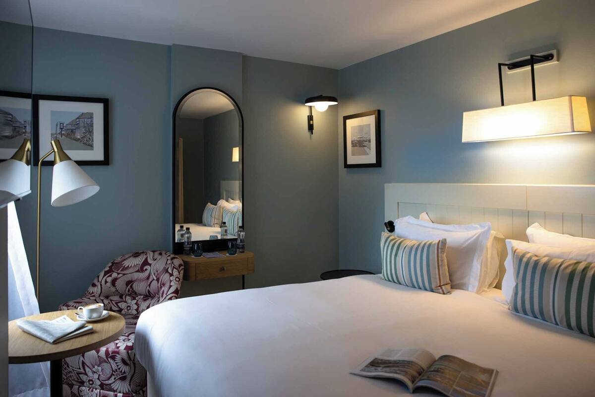 Een hotelkamer met een bed, een bureau met een lamp, een stoel en een spiegel.