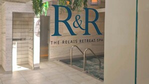 L’intérieur d’un spa, avec un grand logo « R&R », un espace piscine et des lampes suspendues.