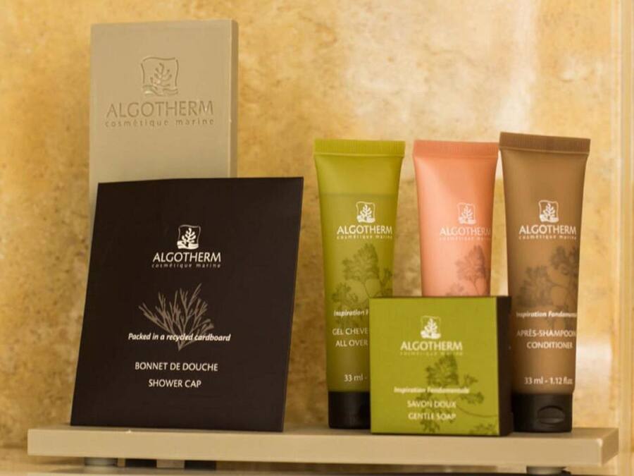 Estante con varios productos ALGOTHERM, incluyendo gorro de ducha, gel y champú.