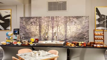 Habitación de hotel moderna con barra de desayuno, zona de estar y un mural temático de bosque.