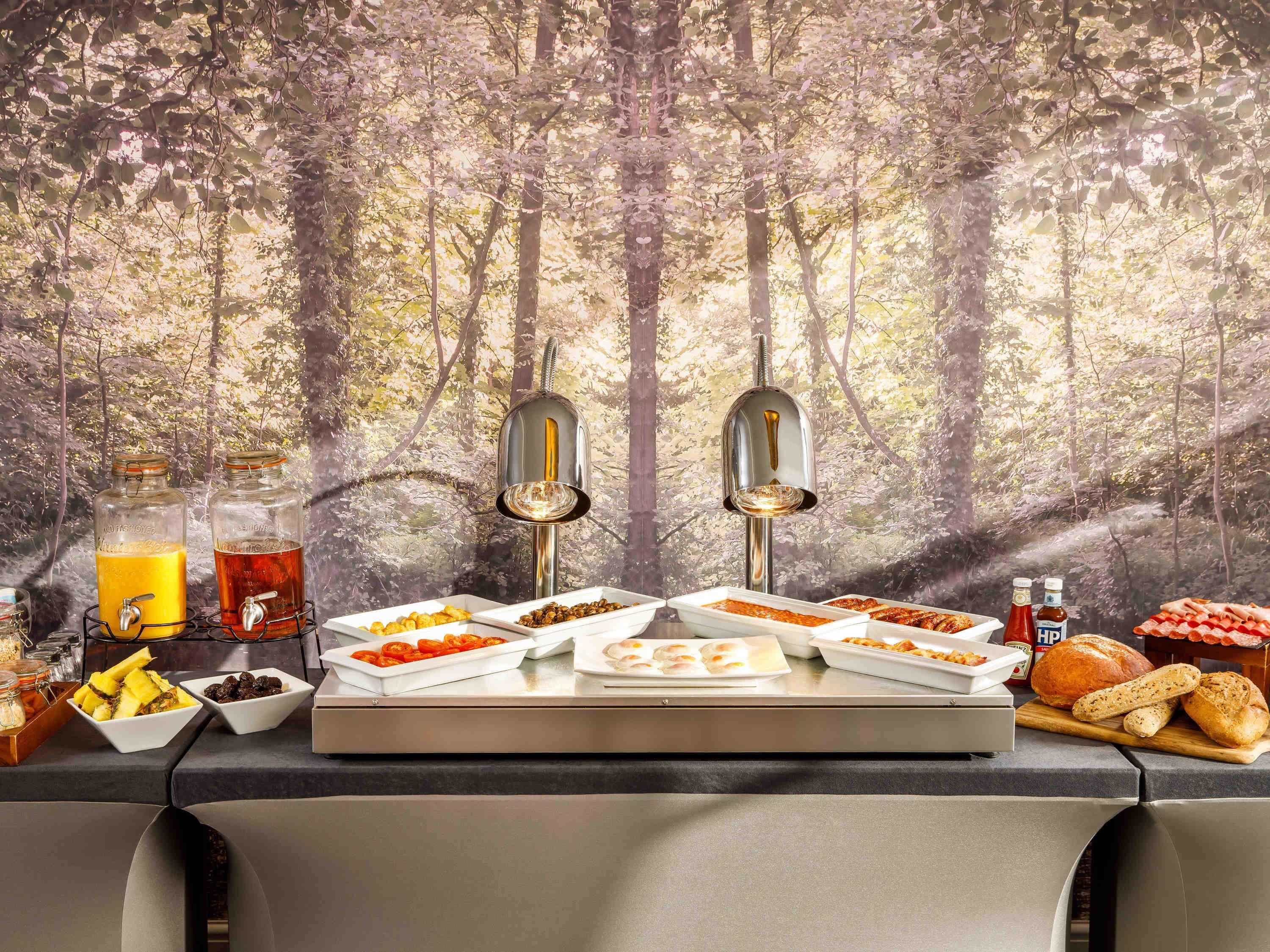 A breakfast buffet with various food items and a juice dispenser.