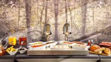 A breakfast buffet with various food items and a juice dispenser.