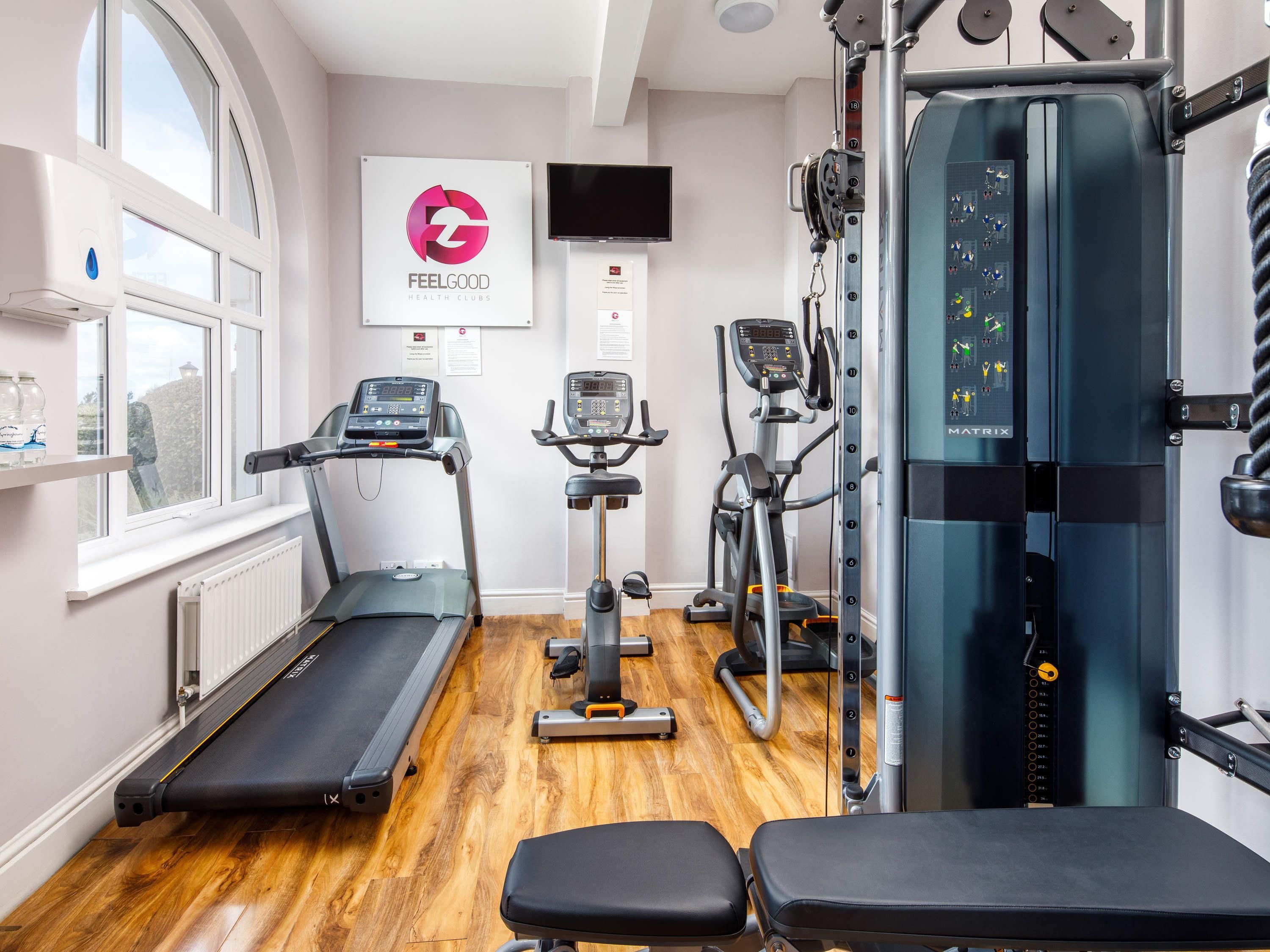 Un gimnasio con cintas de correr, elípticas y máquinas de pesas.