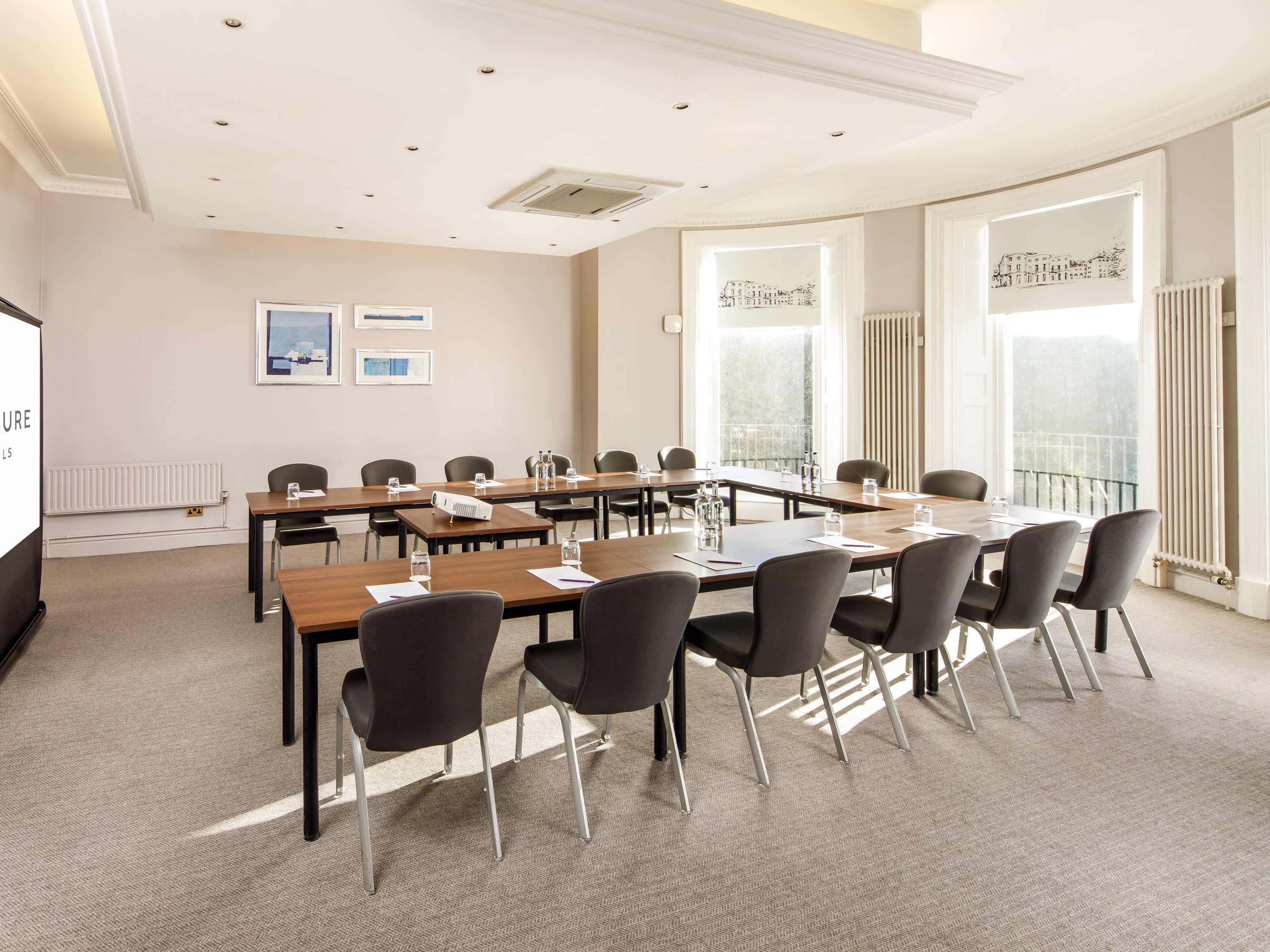 A conference room with a long table, chairs, a projector, and a large window with a view.