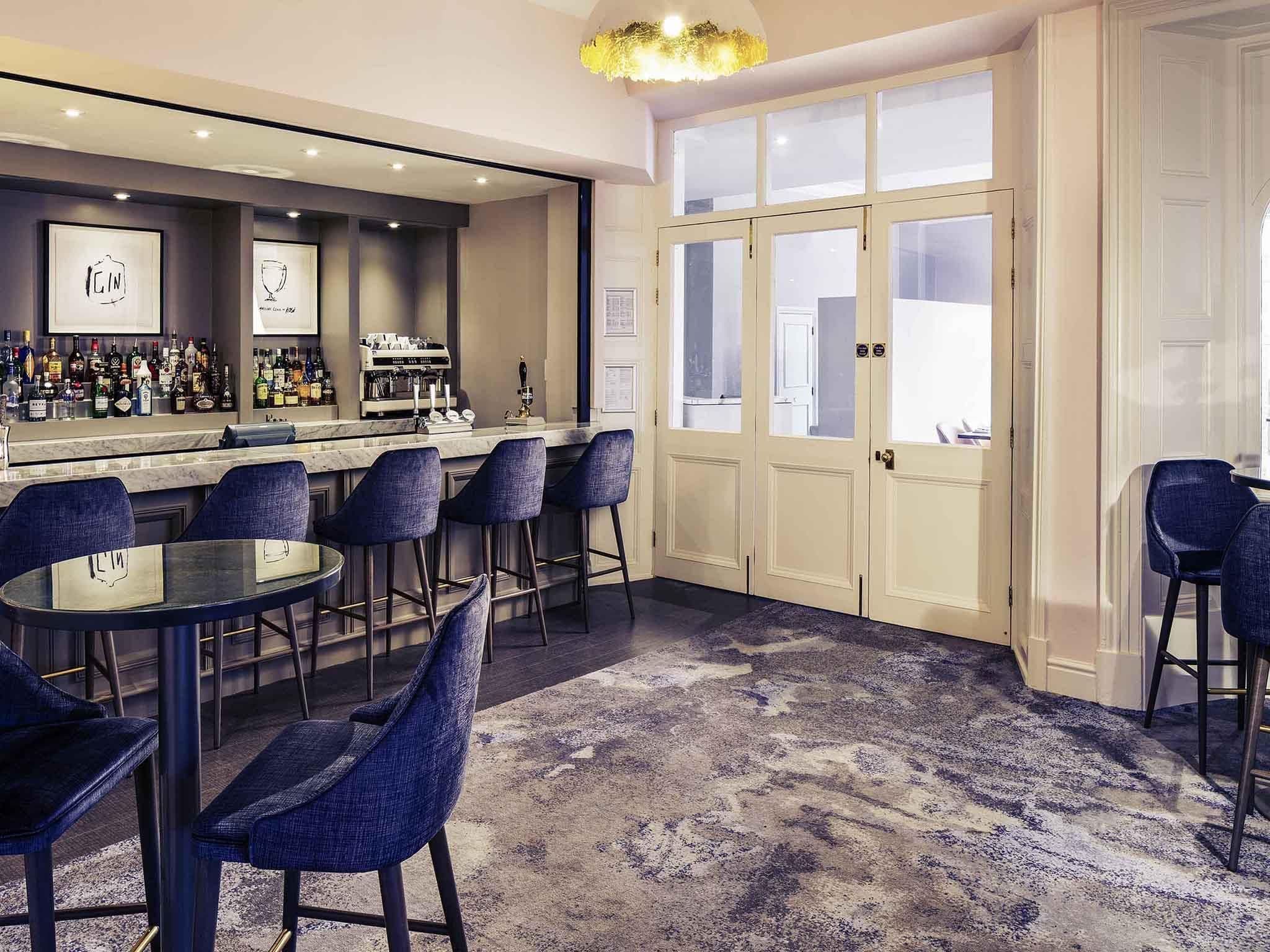 Een bar met een toog, meerdere krukken en een vloerkleed.