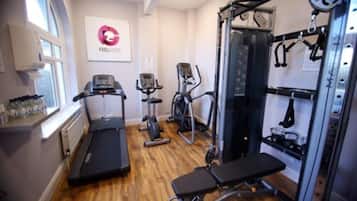 A gym with treadmills, elliptical machines, a bench, and weightlifting equipment.