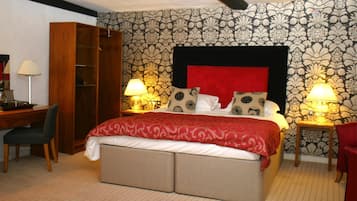 A bedroom with a bed, bedside lamps, a desk, and a wardrobe.
