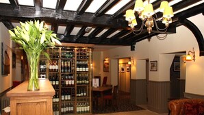 A bar area with a wine rack, a wooden table, and a sofa. - The Bear Hotel by Greene King Inns (Hungerford)