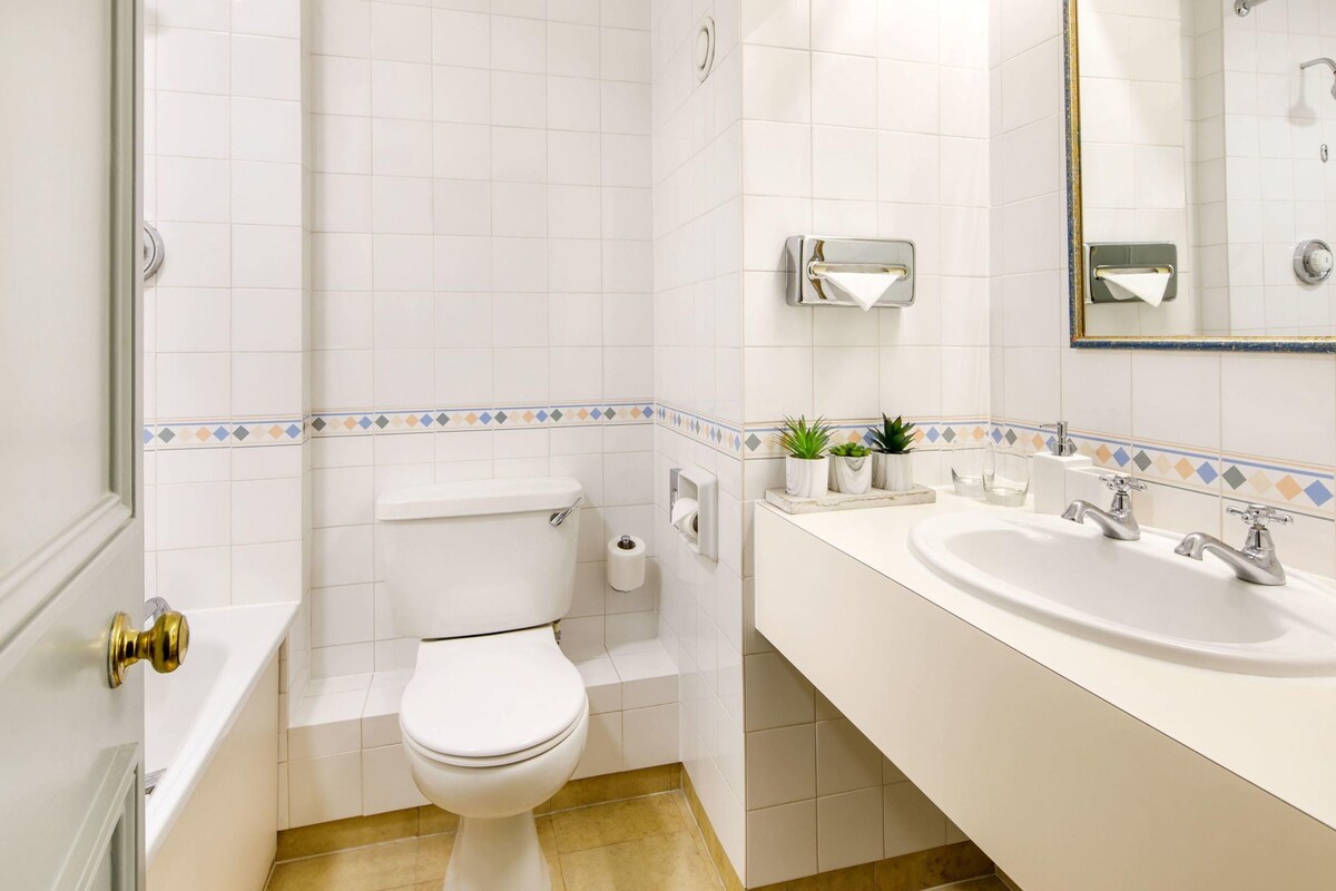 A bathroom with a toilet, sink, and mirror.