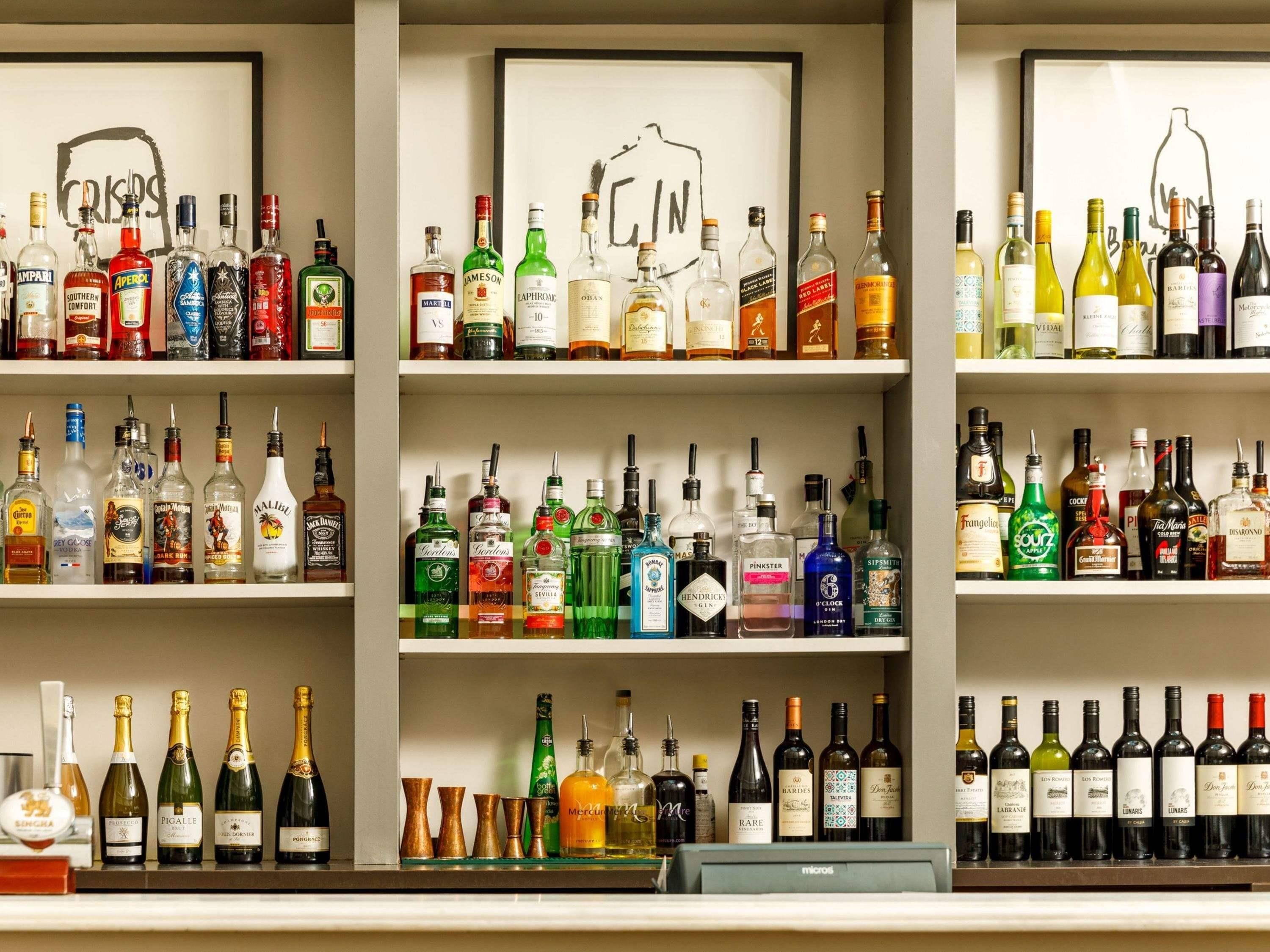 A bar with multiple shelves of various liquor bottles.