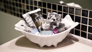 Ein weißes Waschbecken mit verschiedenen Zeitschriften und einer Taschentuchbox auf einer Arbeitsplatte.