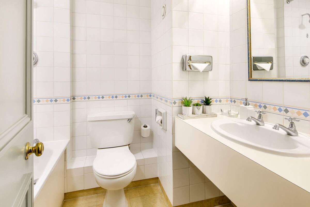 A bathroom with a toilet, sink, and mirror.