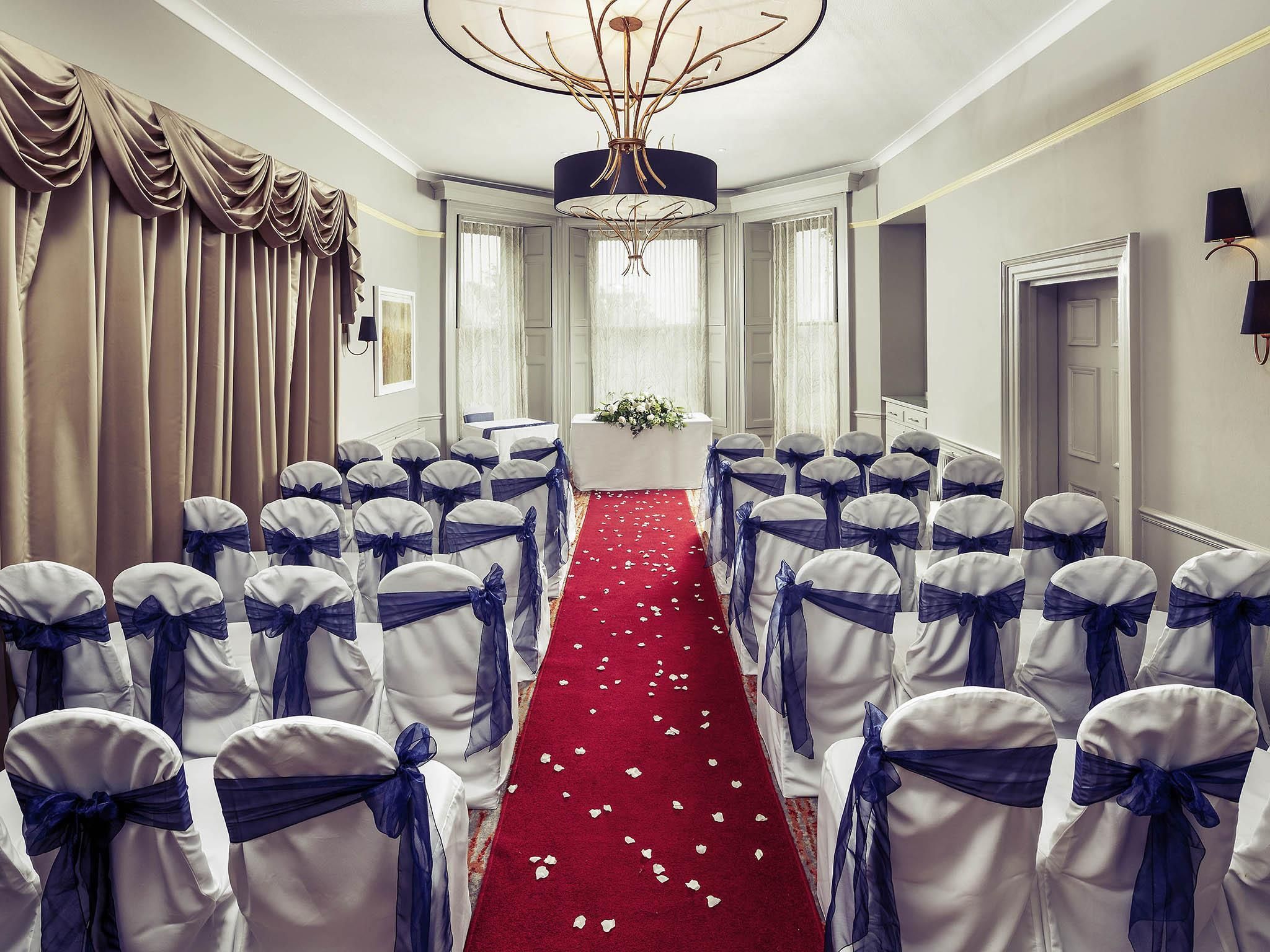 A hotel room with a red carpet, white curtains, and a chandelier.
