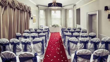 A hotel room with a red carpet, white curtains, and a chandelier.