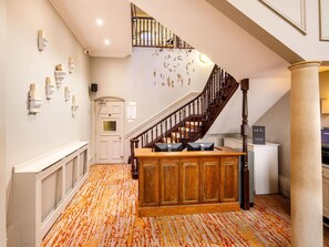 Un hall d’hôtel avec un escalier en bois, un comptoir d’accueil et une moquette à motifs.