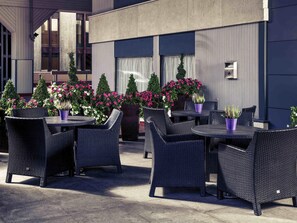 An outdoor seating area with wicker furniture and potted plants. - Mercure Manchester Piccadilly Hotel (Manchester)