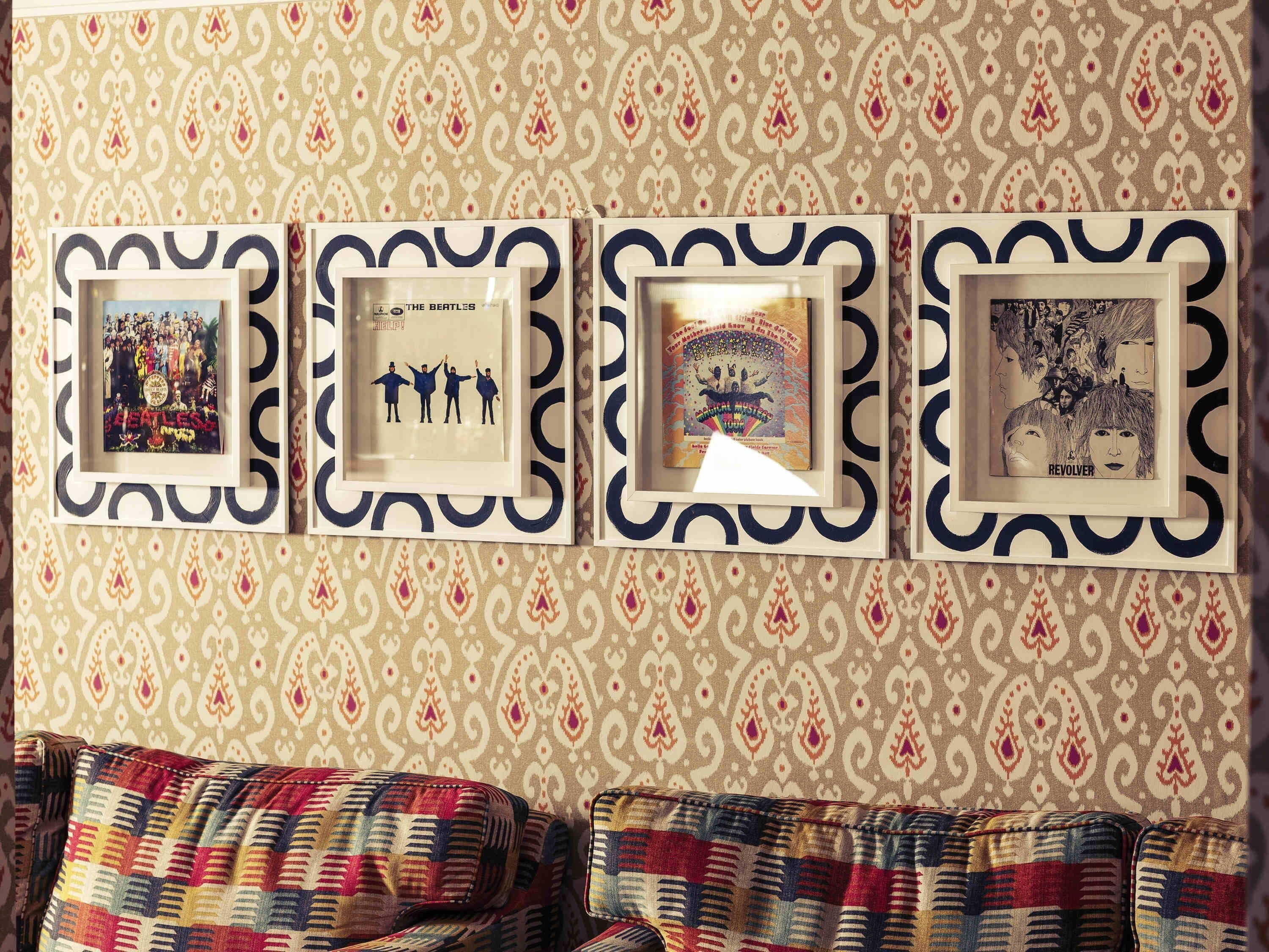 Eine Wand mit gemustertem Wandpapier und vier gerahmten Bildern.
