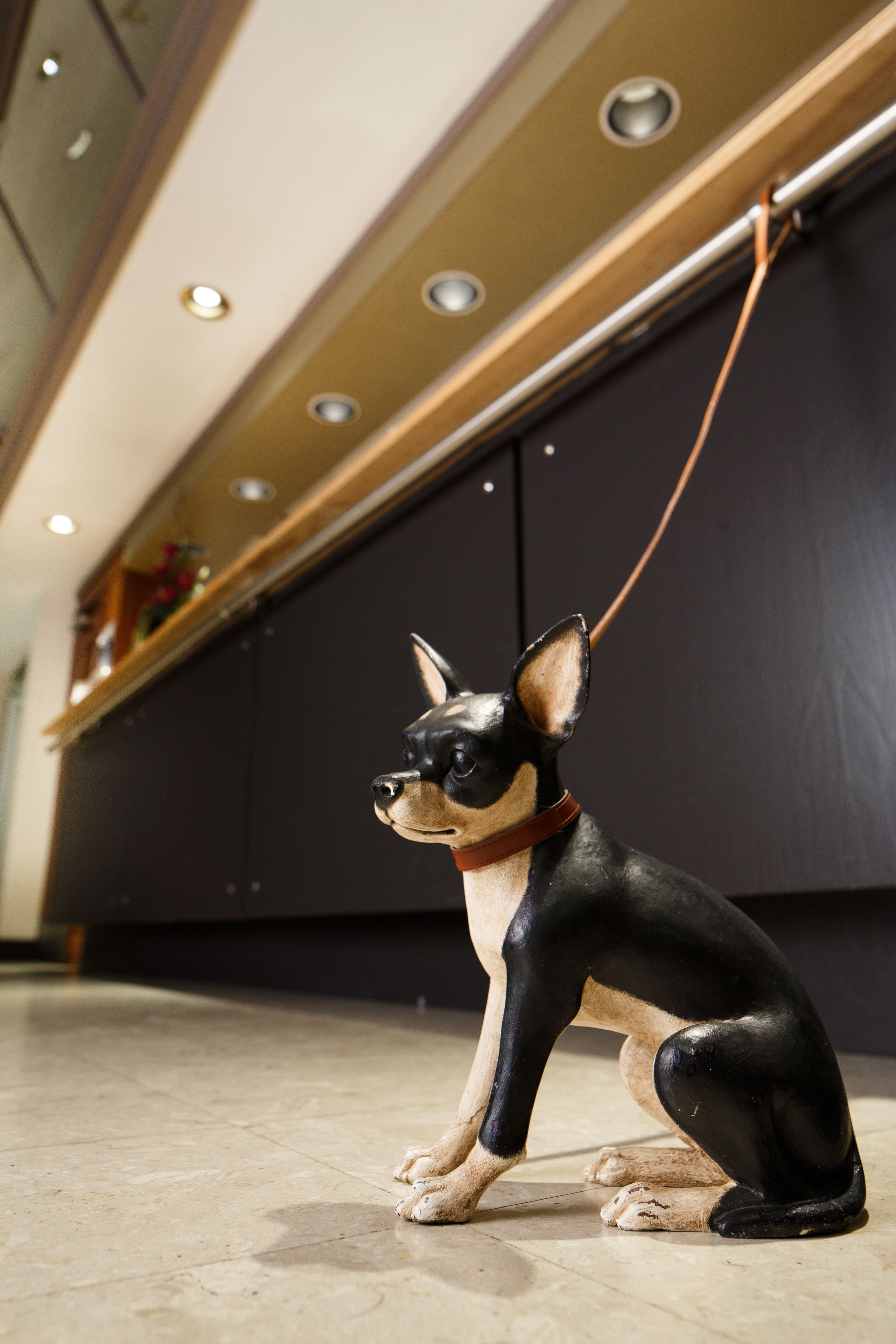 A small dog statue in a lobby with a tiled floor and a dark wall.