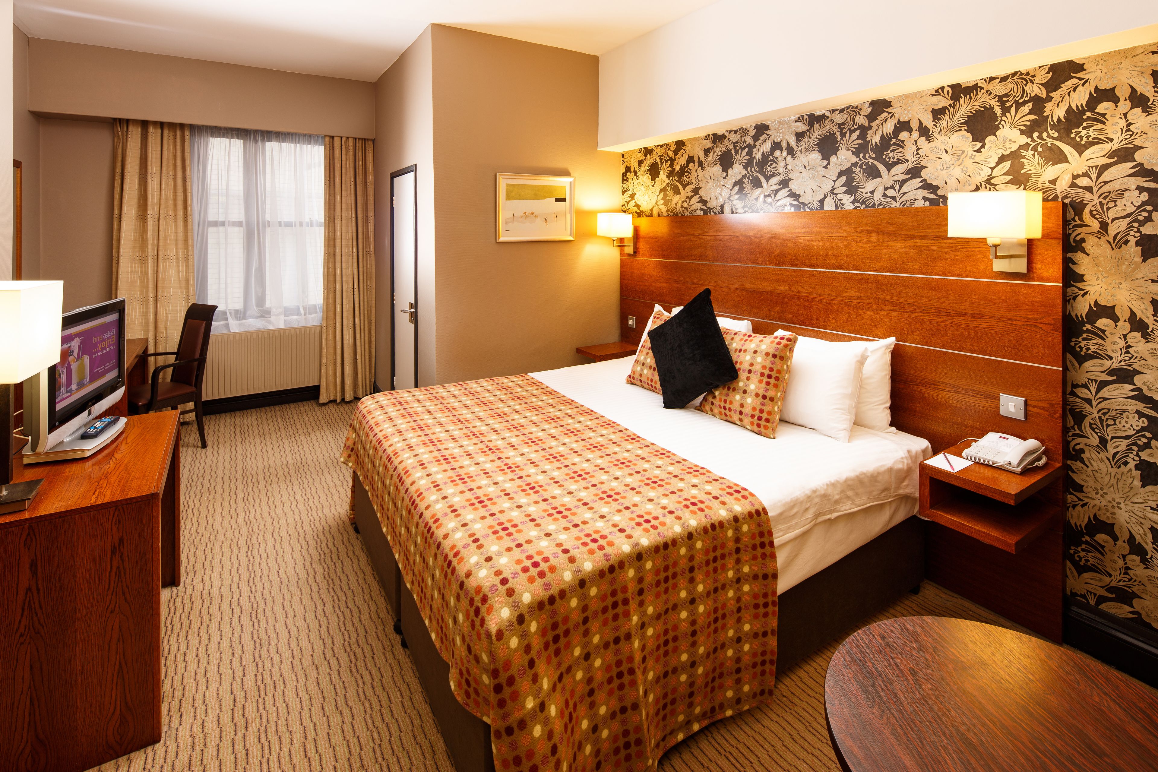 Une chambre d’hôtel avec un grand lit, un bureau avec un ordinateur, une chaise et une petite table.
