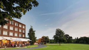 Un hotel con terraza al aire libre, un camino empedrado y una zona ajardinada.