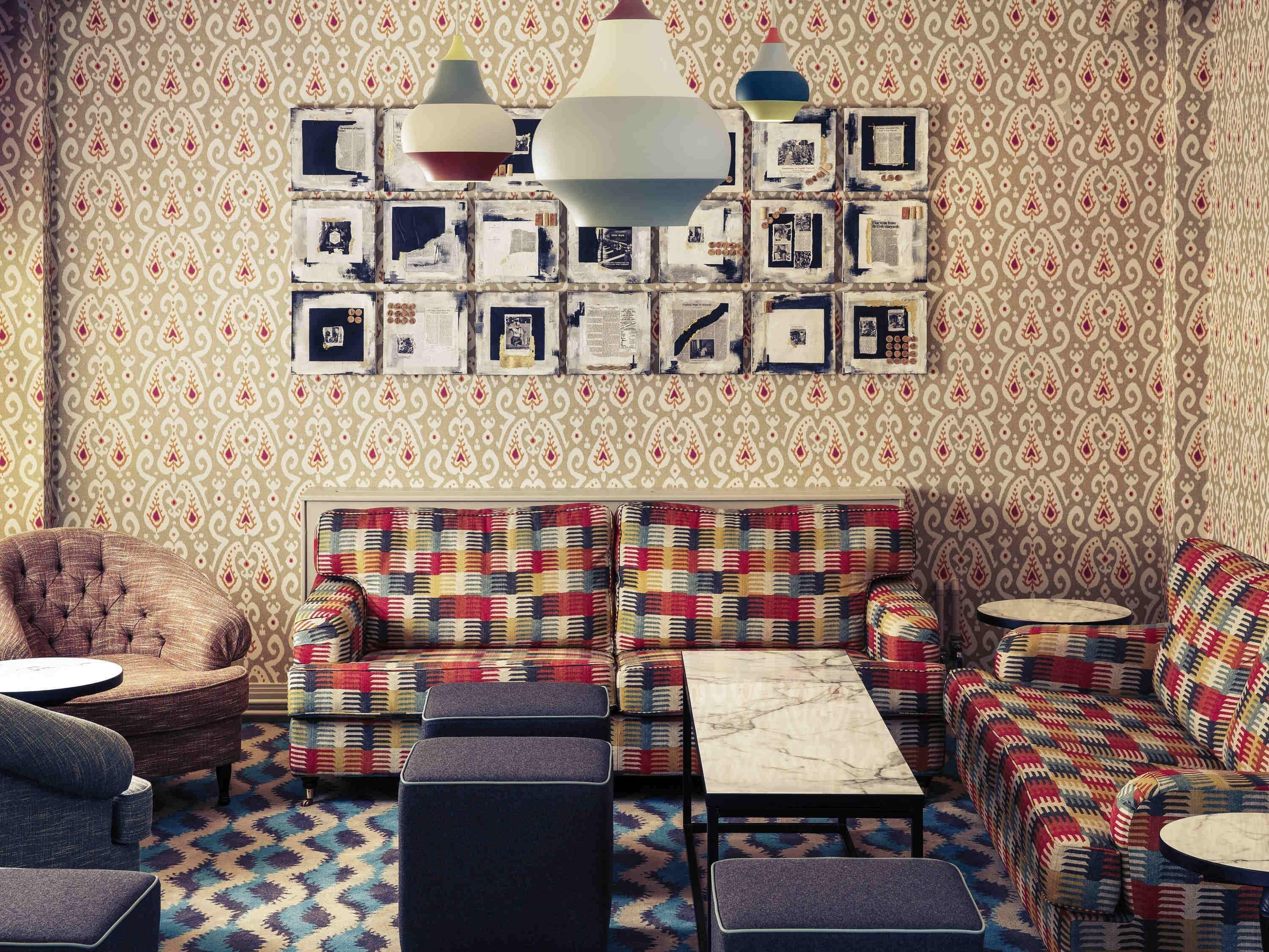 Uma sala de estar aconchegante com papel de parede estampado, um sofá e uma mesa de centro.