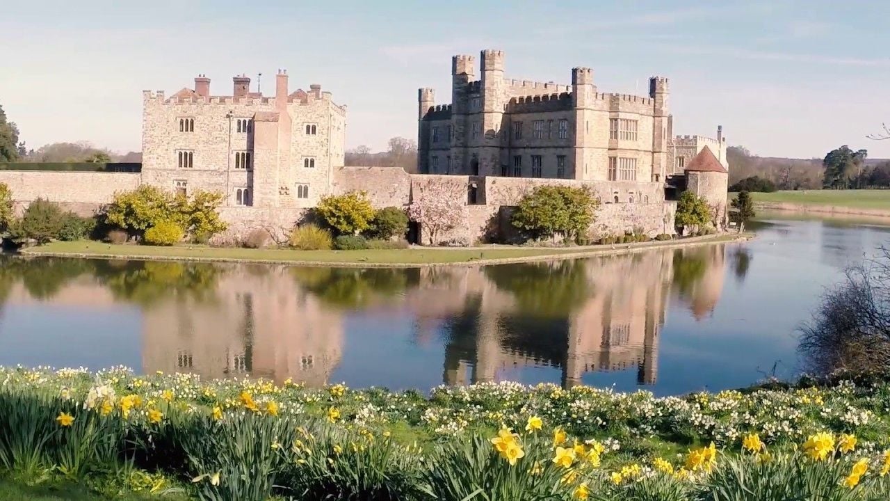Een kasteel met een gracht en narcissen op de voorgrond.