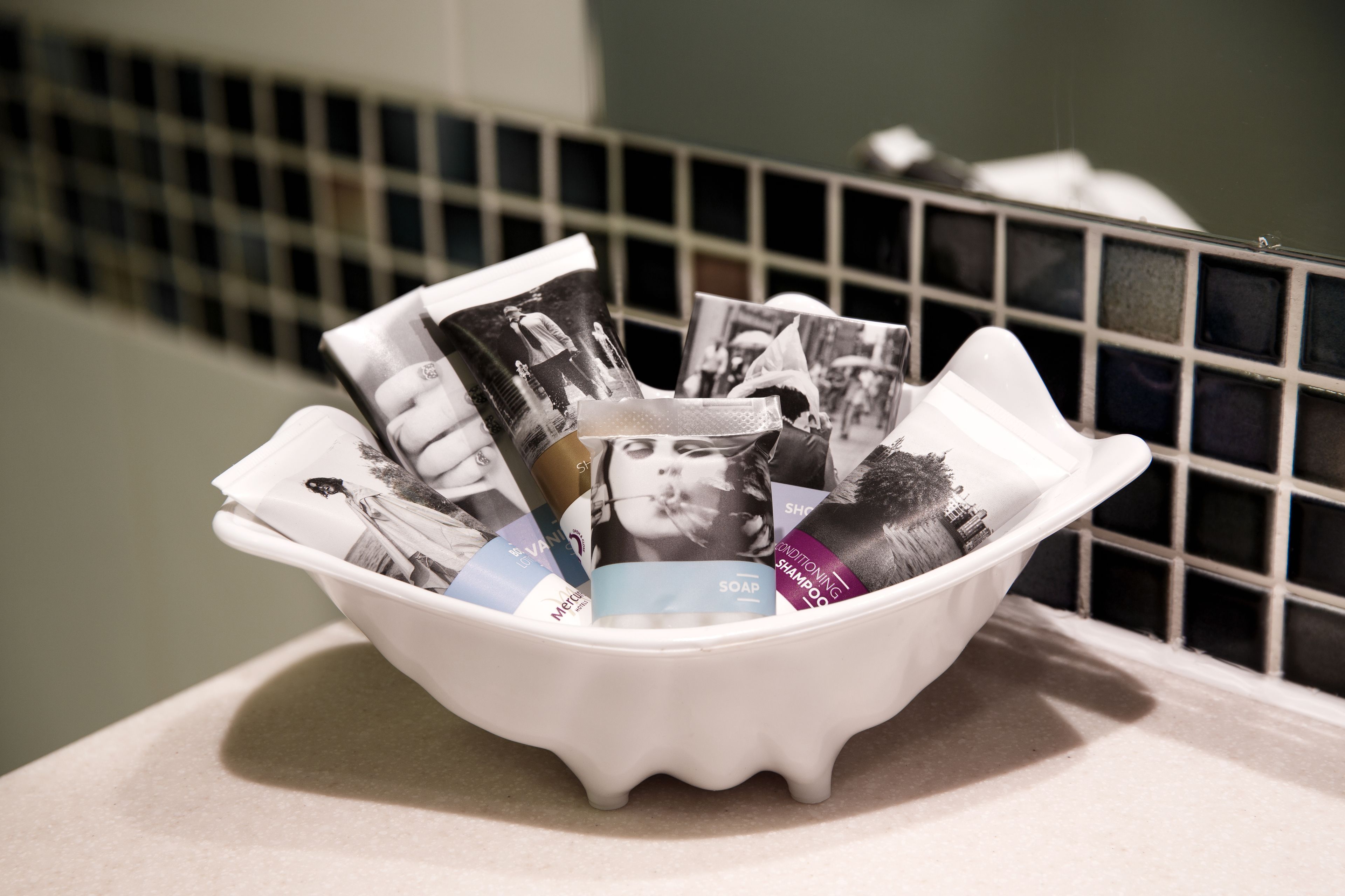 A white basin filled with various magazines and a tissue box on a countertop.
