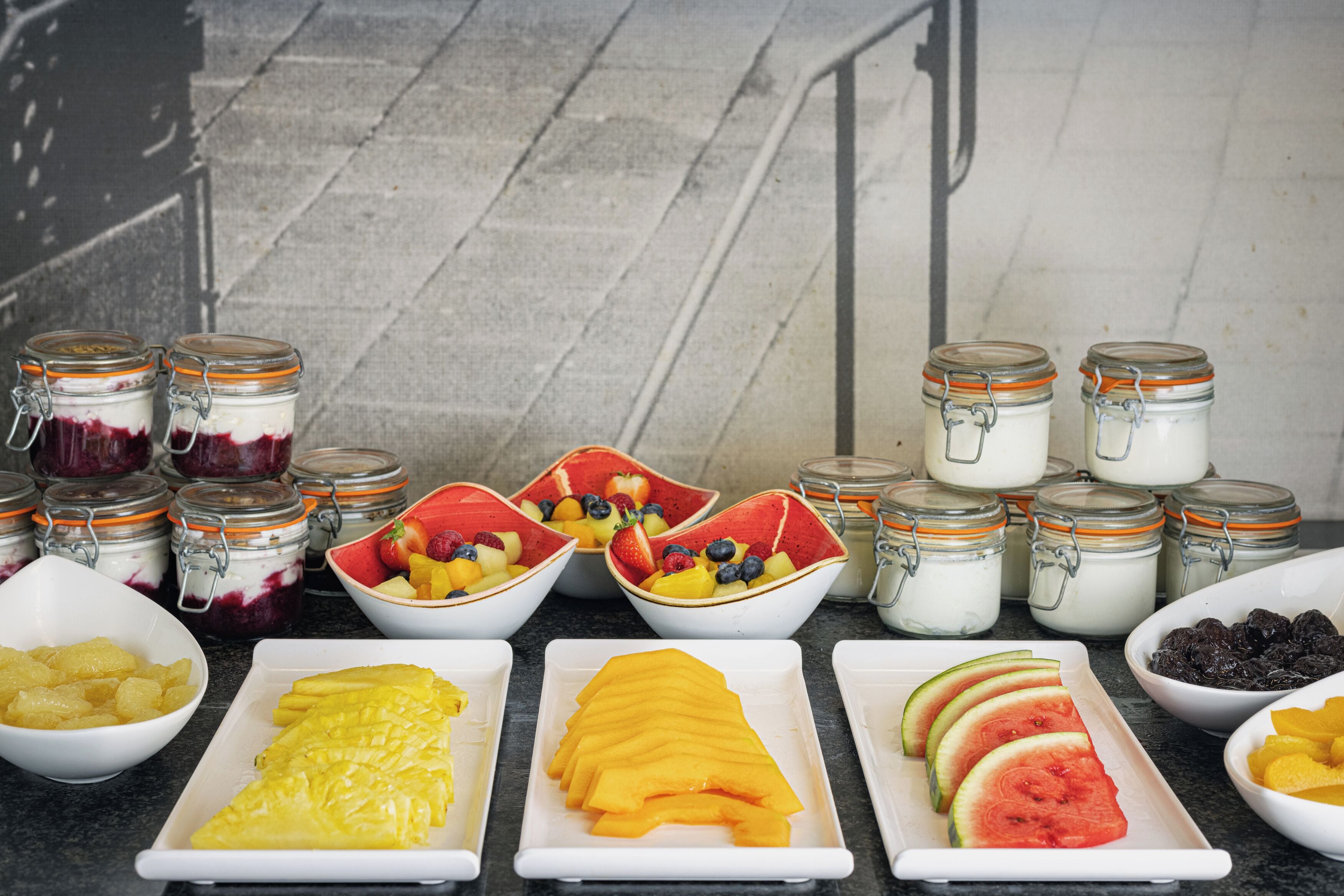 A breakfast buffet with various fruits and yogurt parfaits.