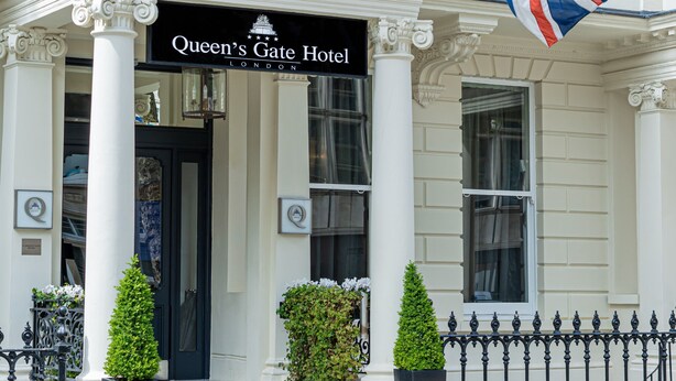 The Queen's Gate Hotel entrance with a British flag, classical architecture, and a black signboard. - The Queen's Gate Hotel (London)