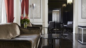 A modern lobby with a leather sofa, a round black table, and a vase of flowers. - The Queen's Gate Hotel (London)
