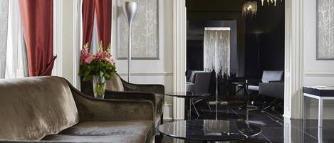 A modern lobby with a leather sofa, a round black table, and a vase of flowers.