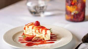A dessert on a plate with a strawberry and a spoon nearby.