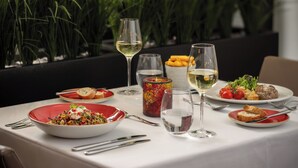 A dining table set with various dishes, glasses, and cutlery, surrounded by indoor plants. - The Queen's Gate Hotel (London)