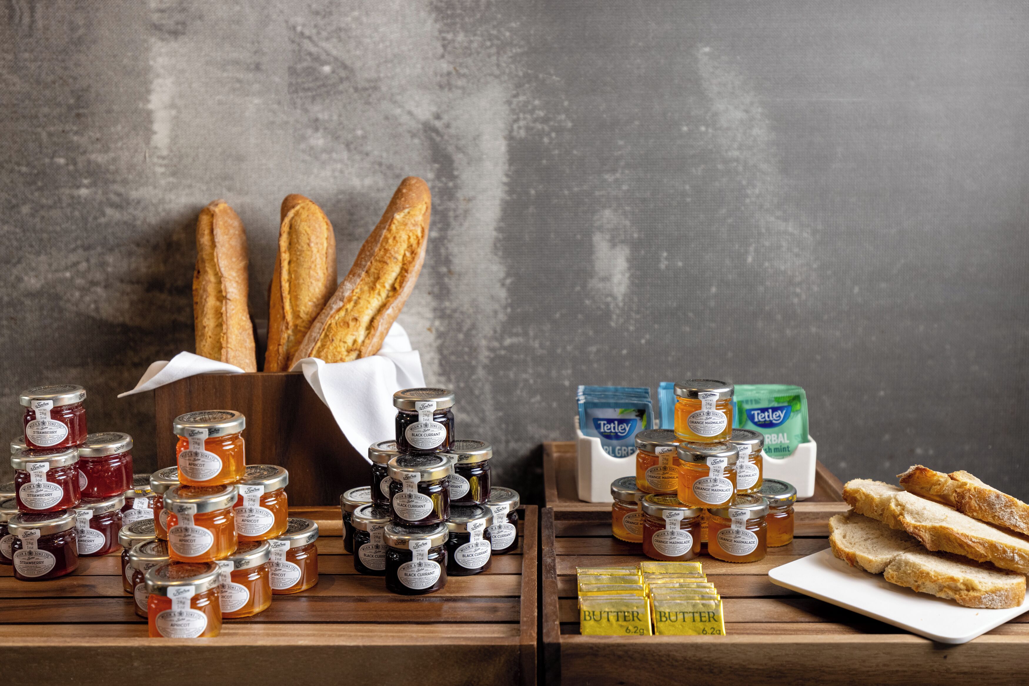 A display of bread, honey jars, and butter blocks on wooden shelves.