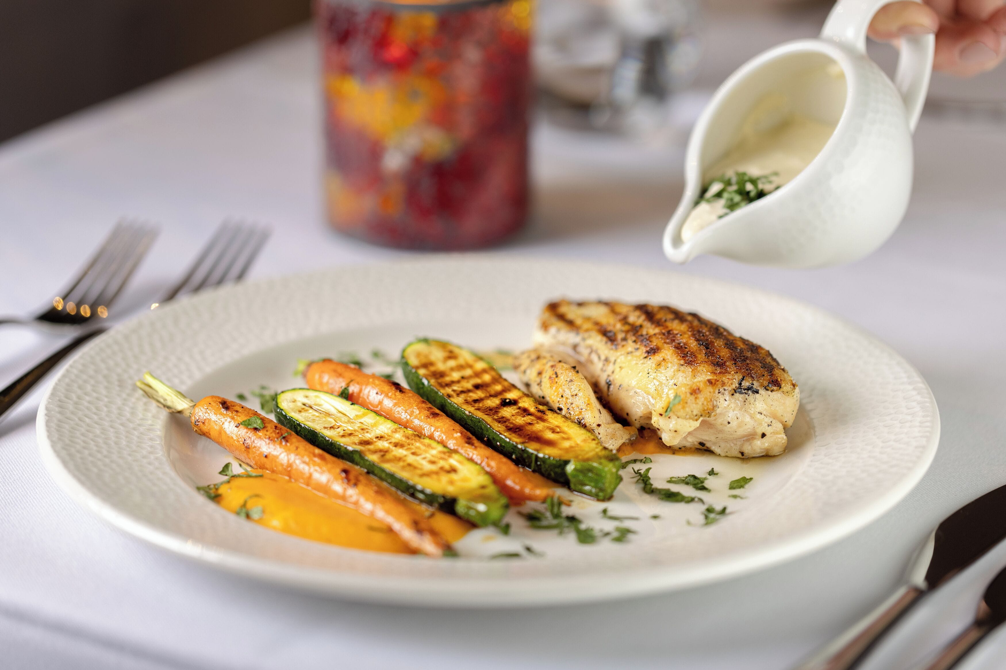 A plate of grilled vegetables and chicken on a white plate.