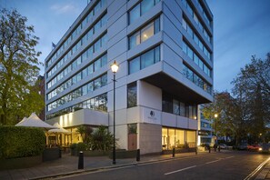A modern hotel with multiple floors, large windows, and outdoor seating areas. - DoubleTree by Hilton Hotel London - Hyde Park (London)