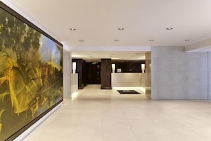 A modern hotel lobby with a large abstract painting, a reception desk, and a tiled floor. - DoubleTree by Hilton Hotel London - Hyde Park (London)