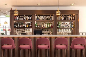 A bar area with multiple shelves of liquor bottles, a bar counter, and four bar stools. - DoubleTree by Hilton Hotel London - Hyde Park (London)