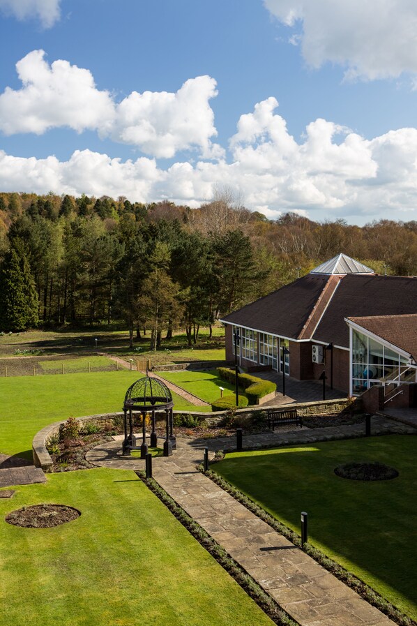 A building with a glass facade, surrounded by a well-maintained lawn and a garden area with a gazebo. - Mercure Leeds Parkway Hotel (Leeds)