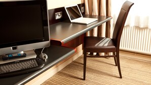 A hotel room with a desk, a laptop, a television, and a chair. - Mercure Leeds Parkway Hotel (Leeds)