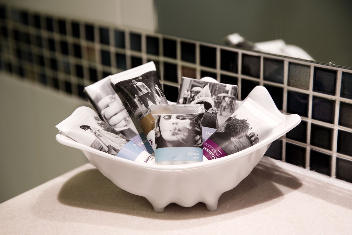 A white basin filled with various magazines and a tissue box on a countertop.