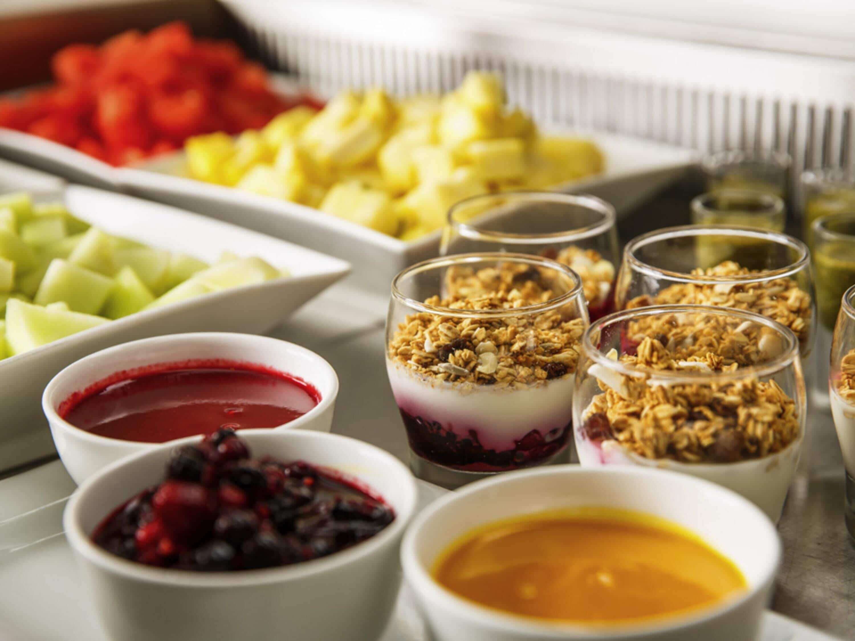A variety of food items including fruits, yogurt parfaits, and a bowl of soup.