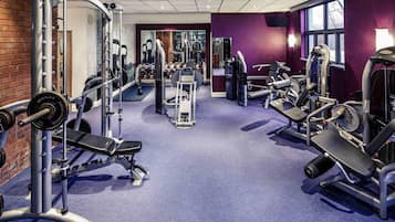 A gym with various exercise equipment, a brick wall, and a purple wall.