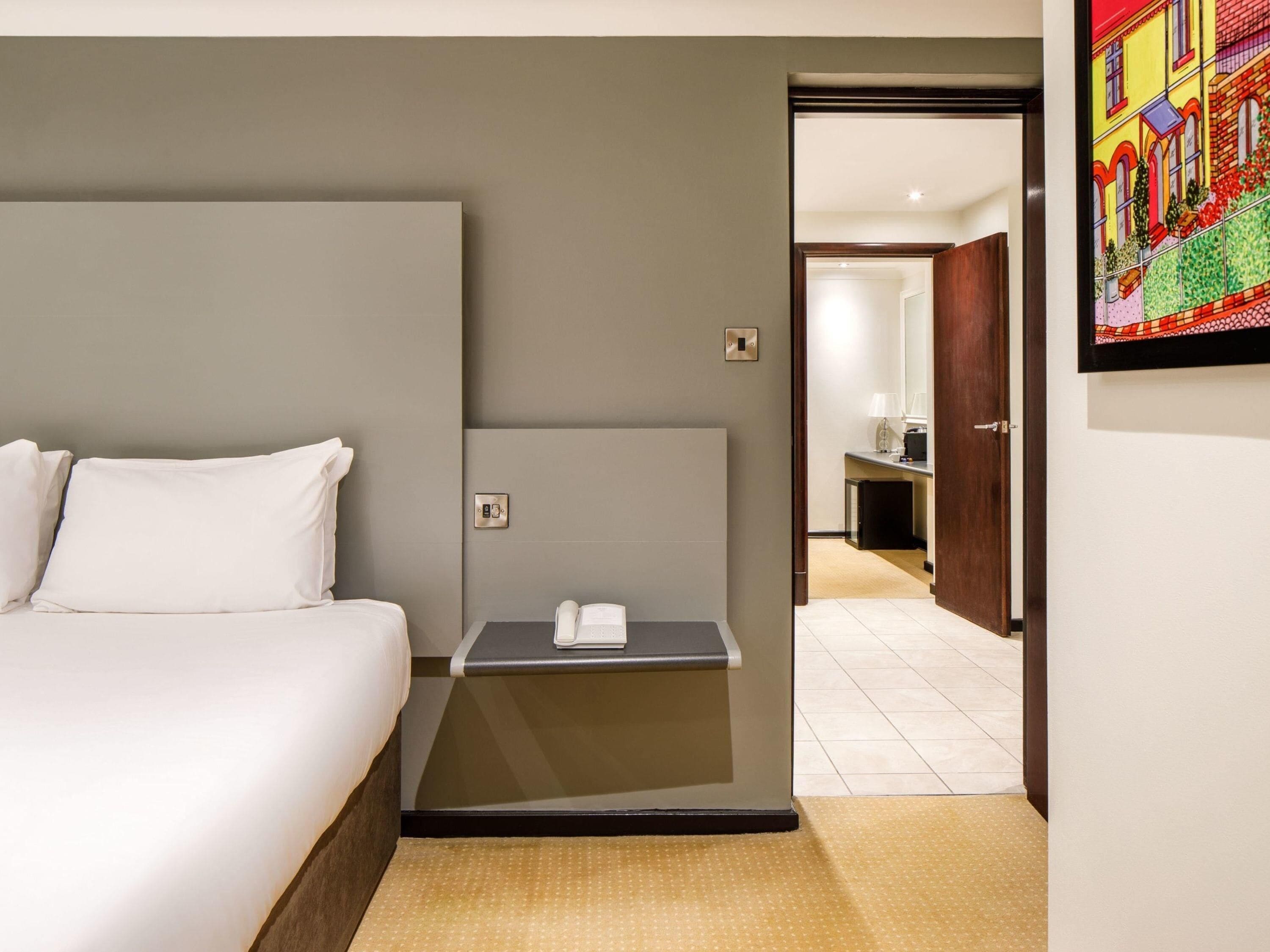 Une chambre d’hôtel comprenant un lit, une table de chevet et une porte donnant accès à une salle de bain.