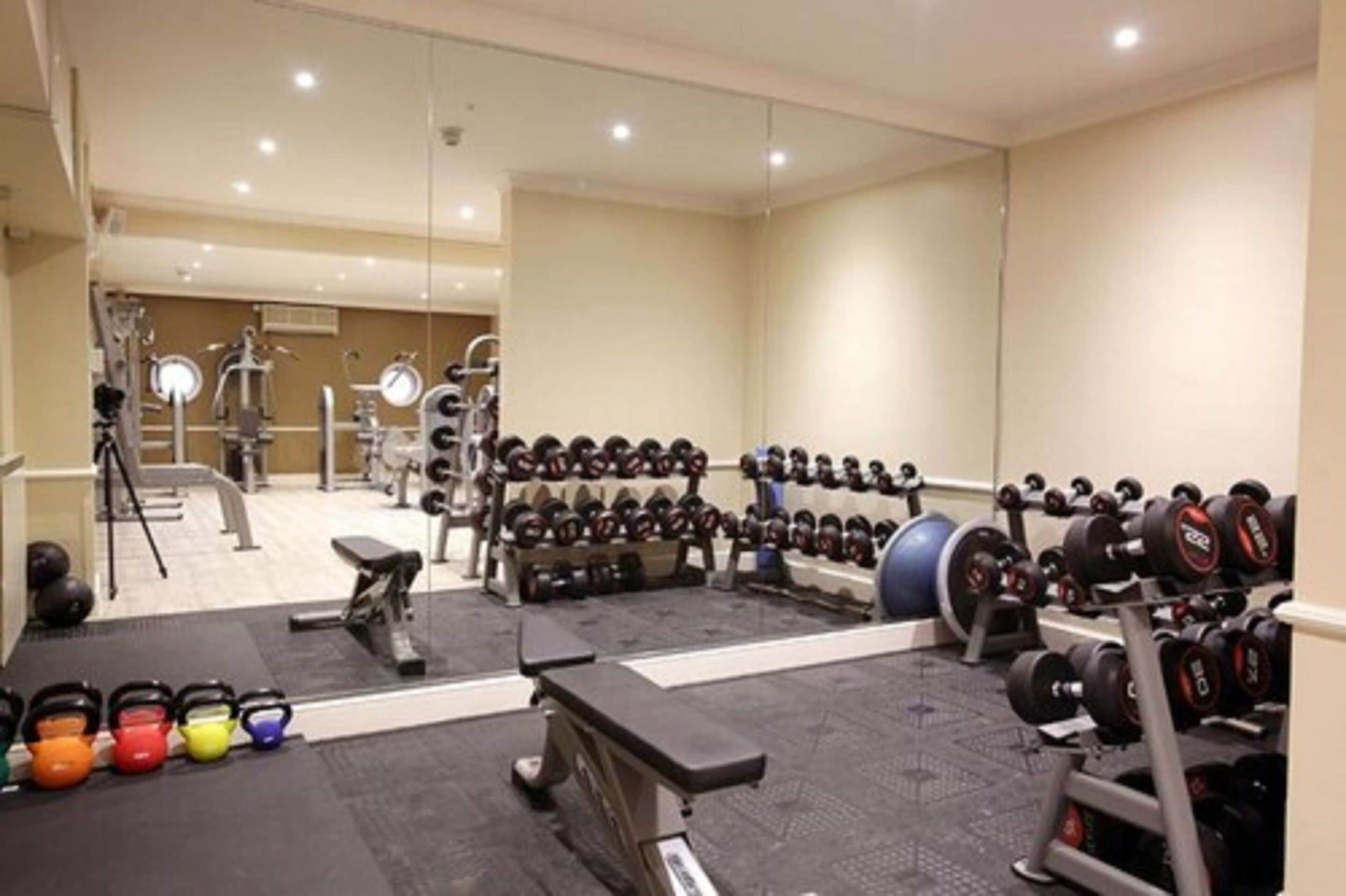 A gym with various exercise equipment, including dumbbells, kettlebells, and weight machines.