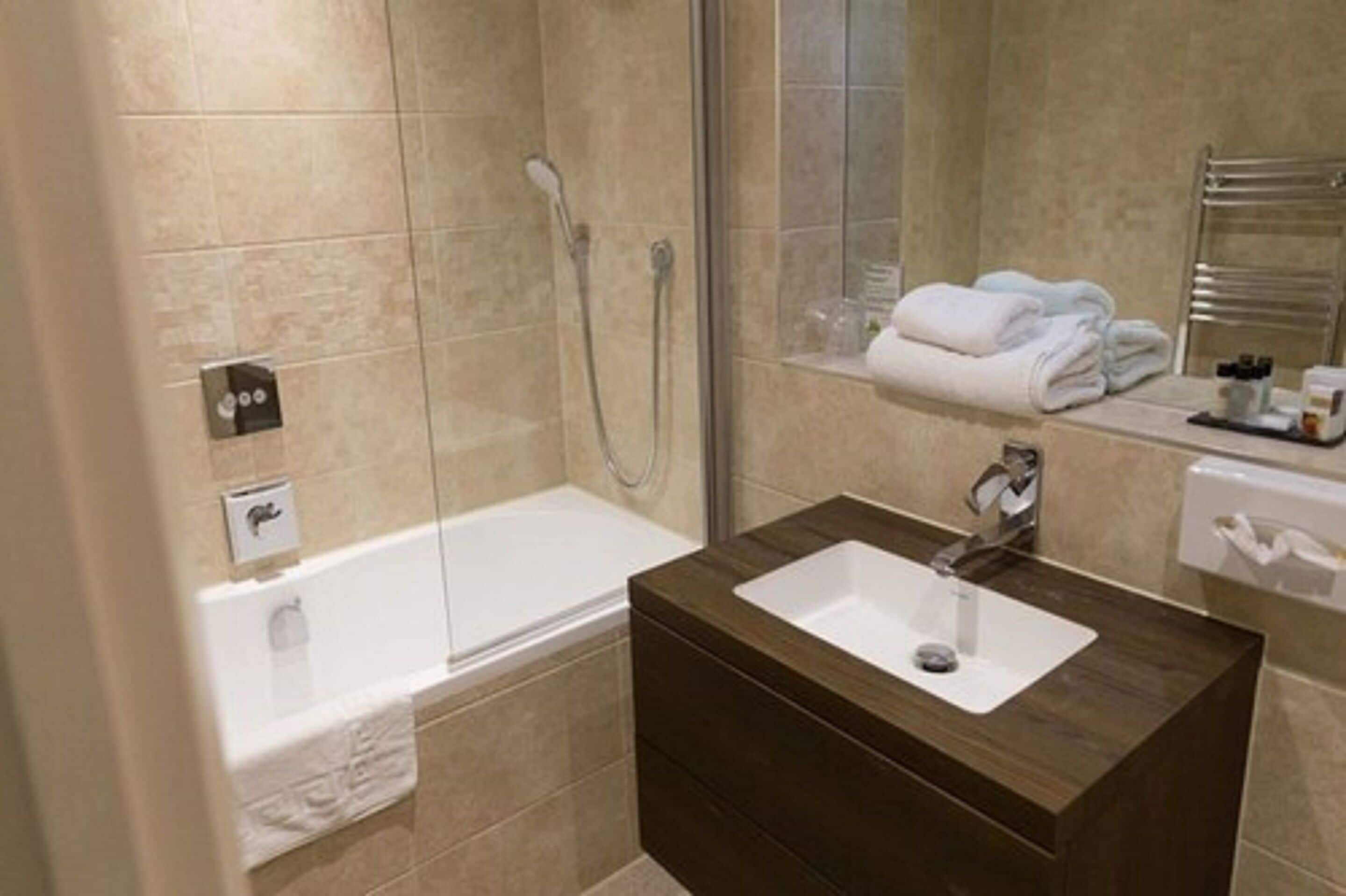 A modern bathroom with a bathtub, a vanity with a sink, and a glass shower enclosure.